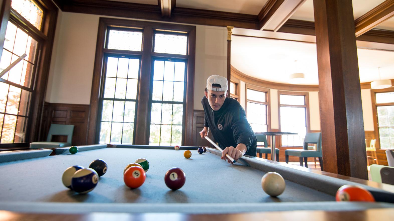A student plays pool in Carlisle Foyer in the Alumni Hall residence hall.