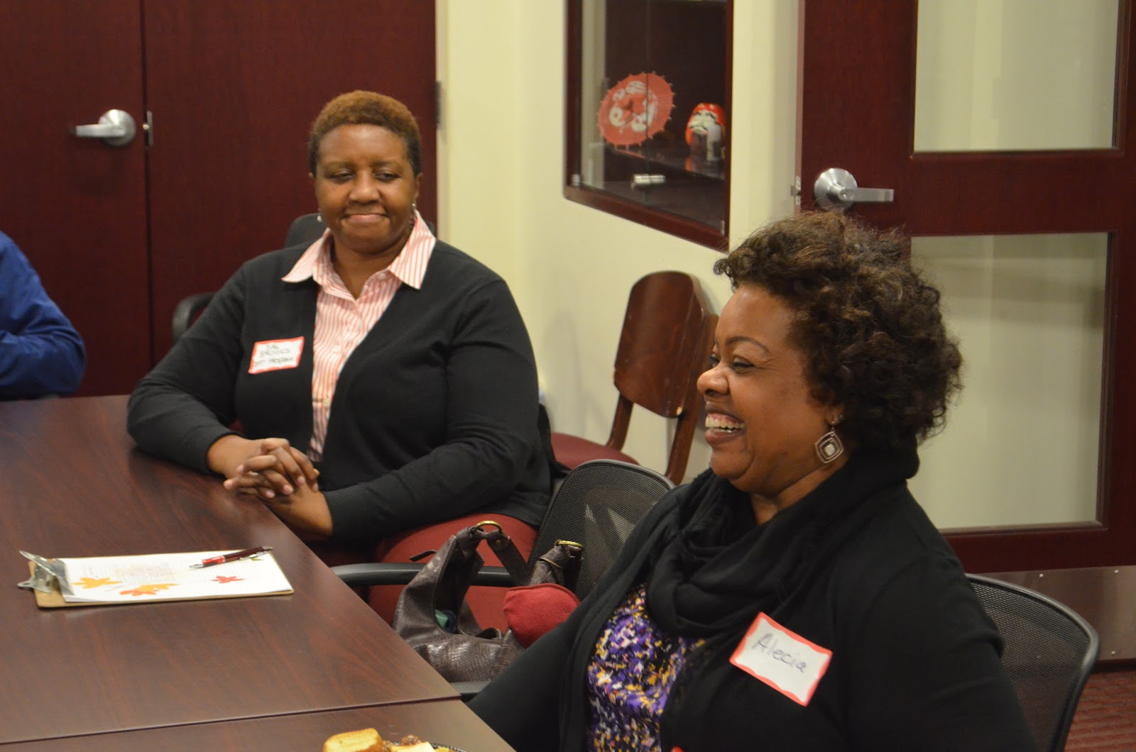 two women laugh while sitting at a table