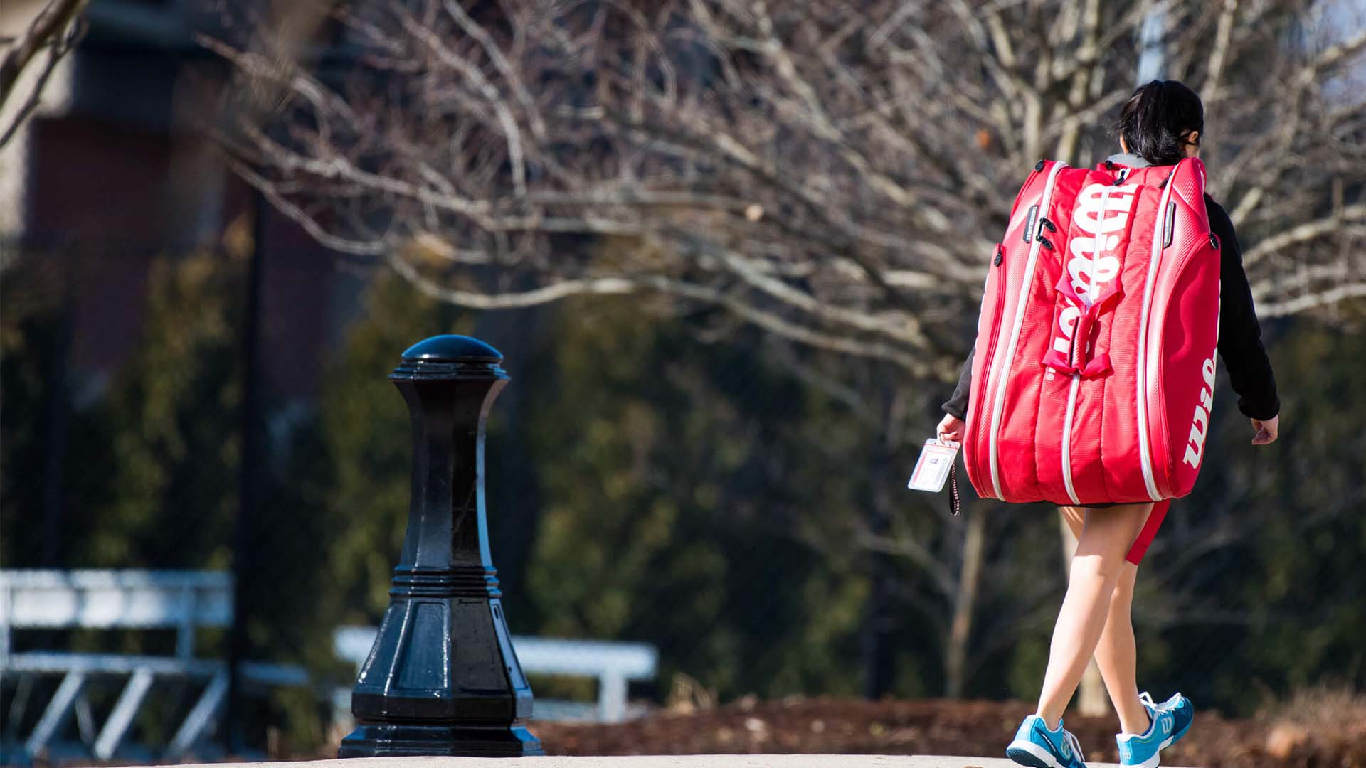 A student walks across the Springfield College campus while lugging a large sports bag on her back. 