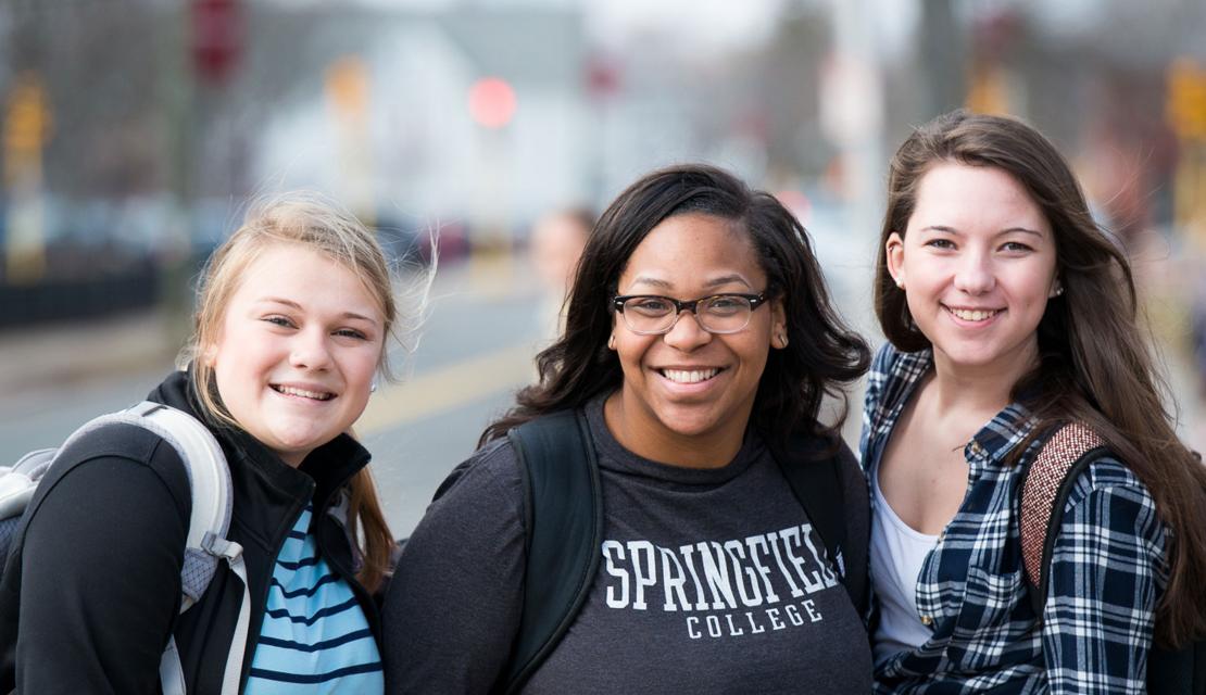Three female students smiling as they walk to class.