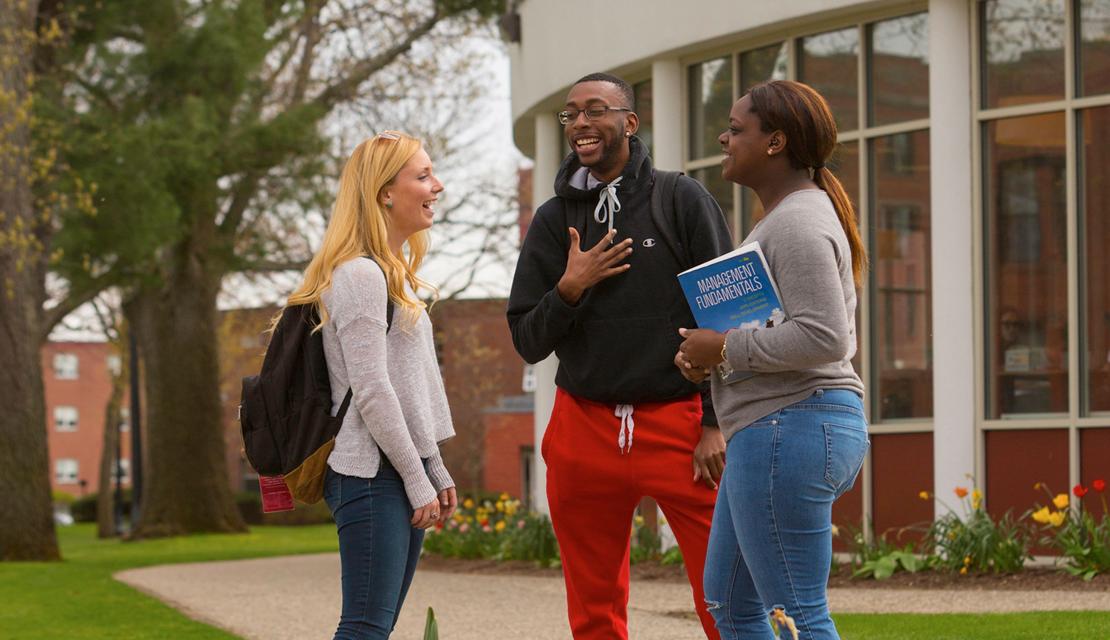 Students talking on a sidewalk on campus during the spring.