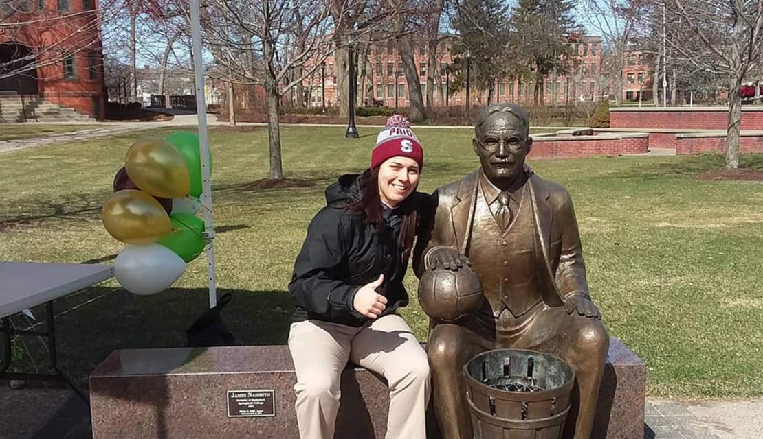 Sam Avery sits next to the James Naismith statue on campus. 