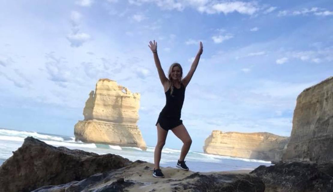 Meghan Godfrey stands on a rock on a beach in Australia. 