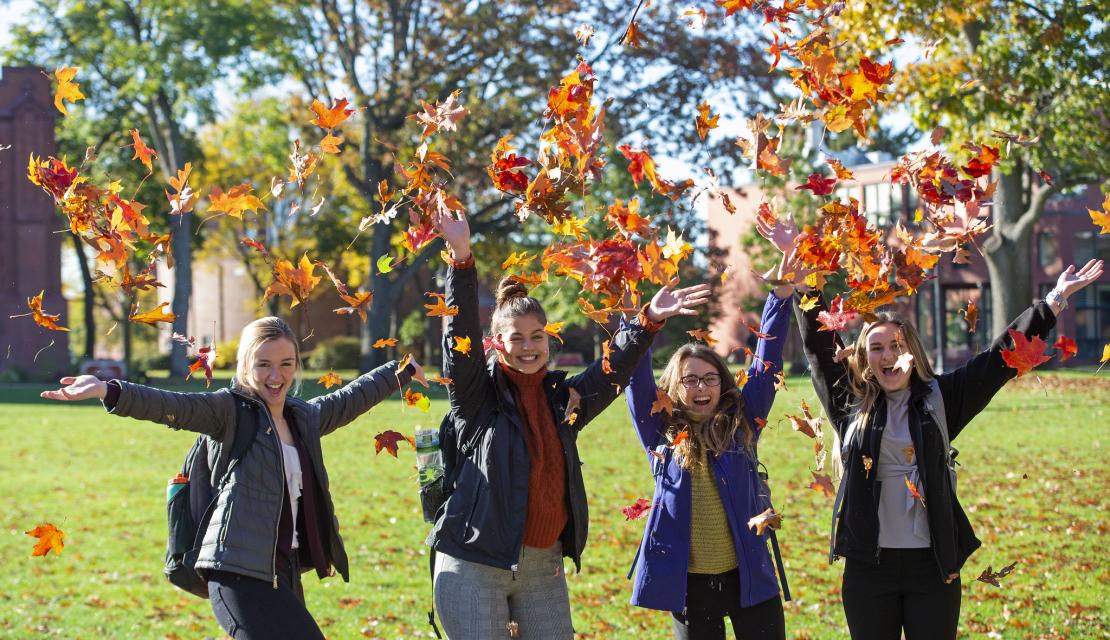 Students throw leaves in the air
