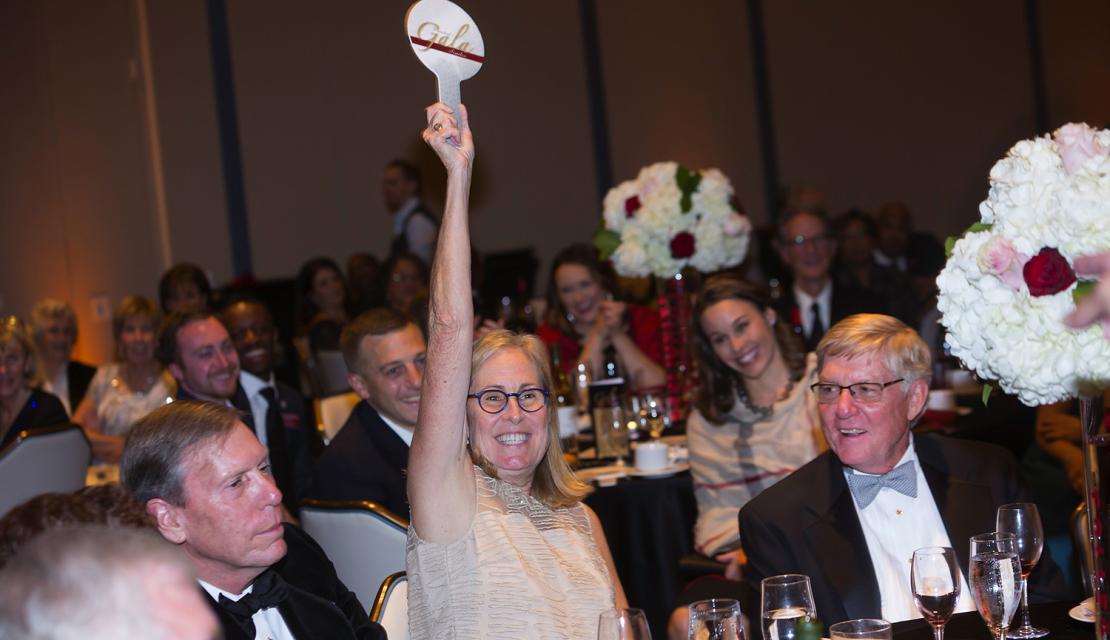 A woman holds up her auction paddle at Gala