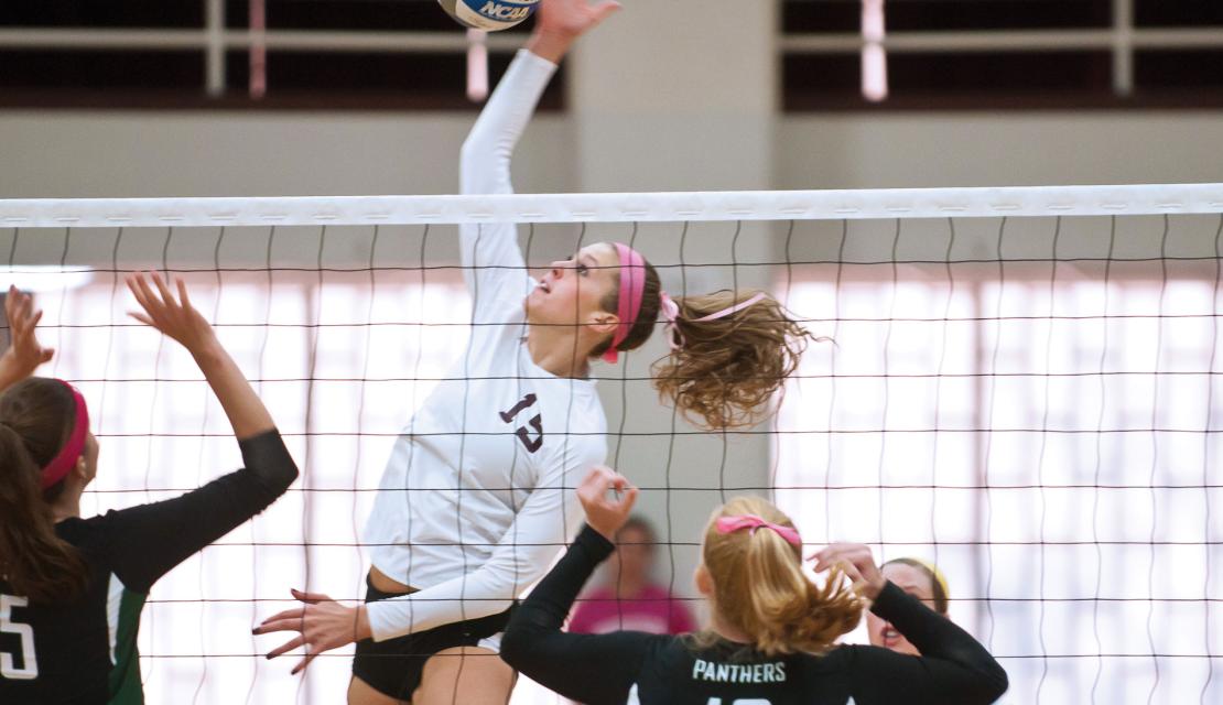 Mary Consol of Springfield College Volleyball spikes a volleyball over the net during a game