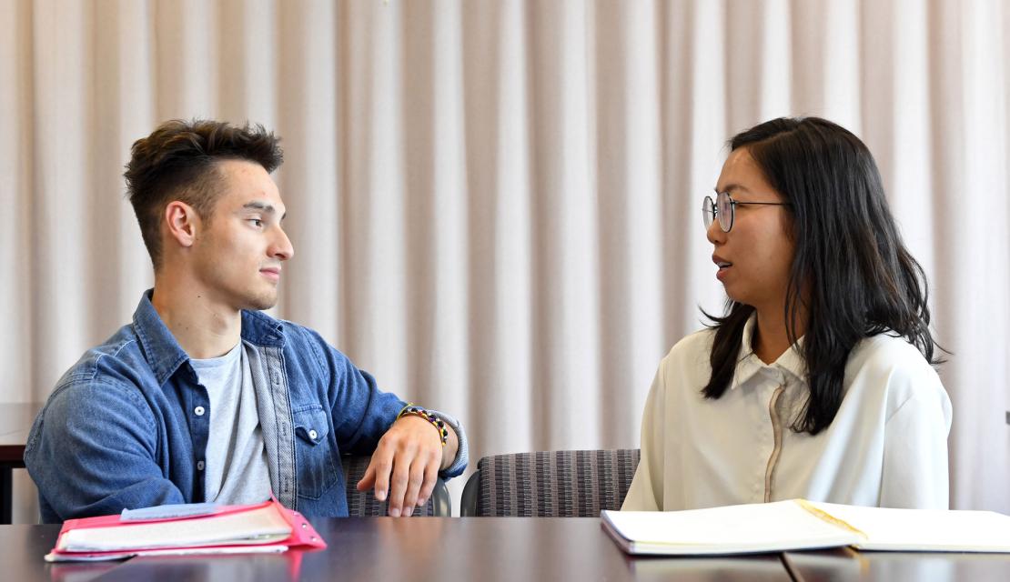 Two students talk in a classroom setting