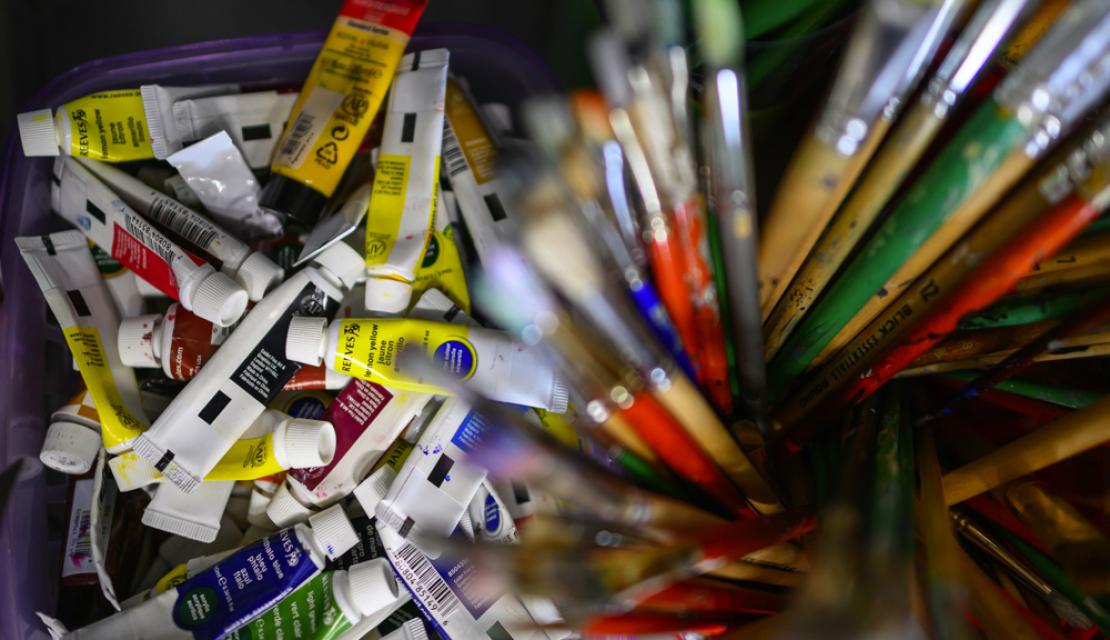 a mix of painting supplies shown on an art desk