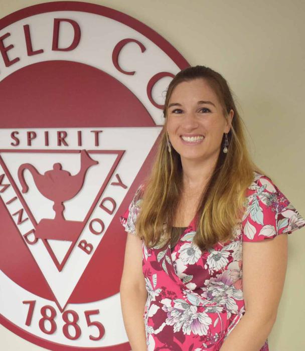 Photo of Joy Erickson in front of Springfield College seal.