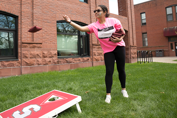 student playing bean bag toss on Naismith green