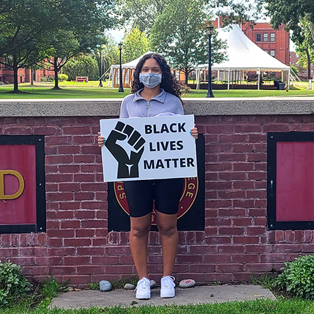 student in front of wall with BLM sign