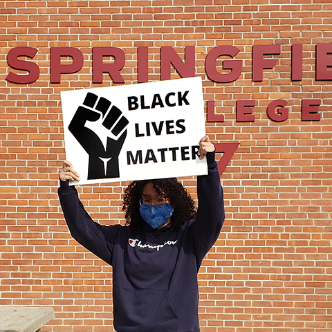 woman holding Black Lives Matter sign in front of Springfield College sign