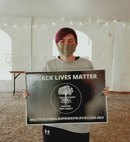 student in tent on Naismith green holding Black Lives Matter sign
