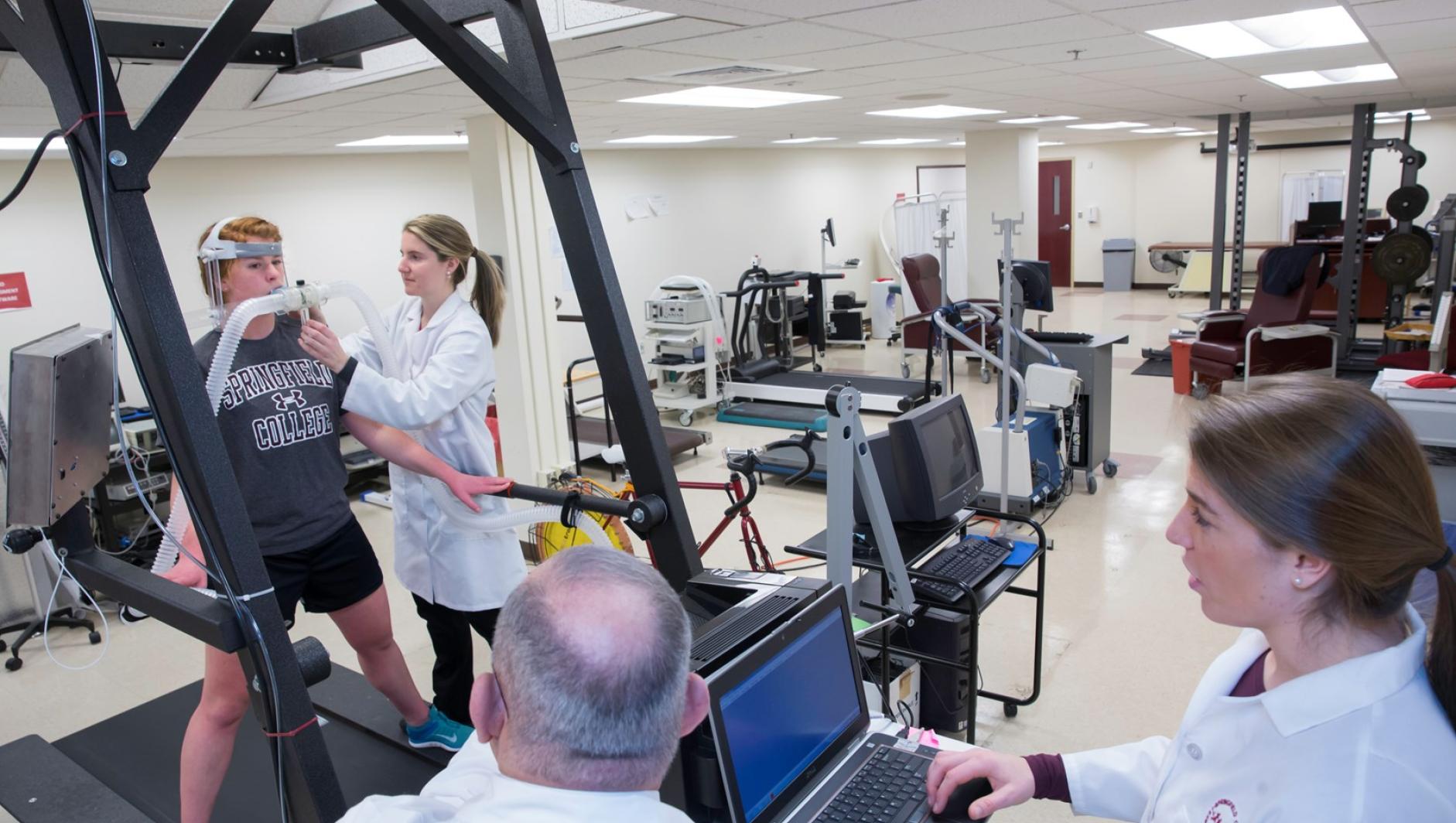 Student and faculty adjust the computer tracking system as a participant runs on the treadmill.