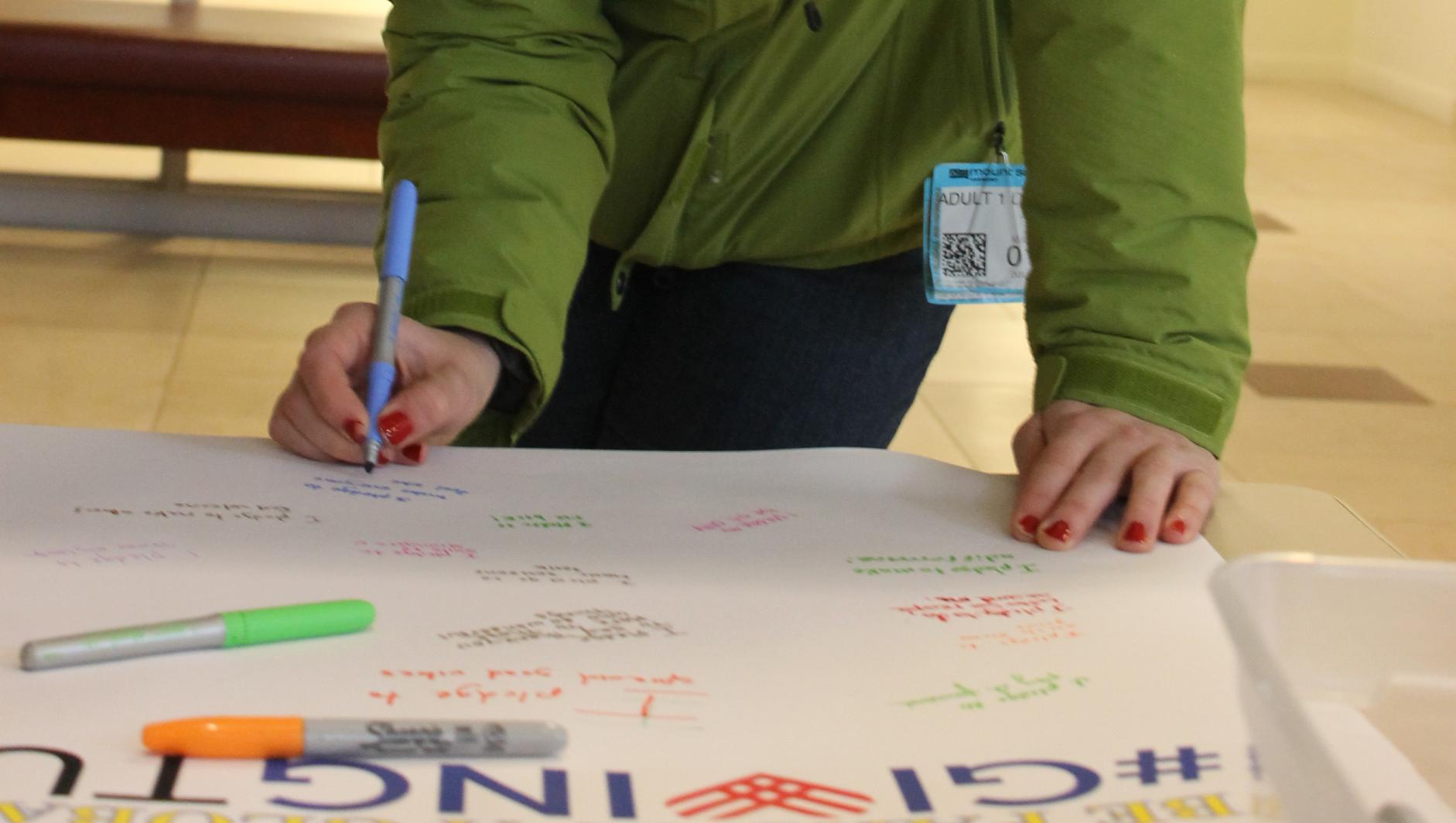 Springfield College student signing poster board during #GivingTuesday