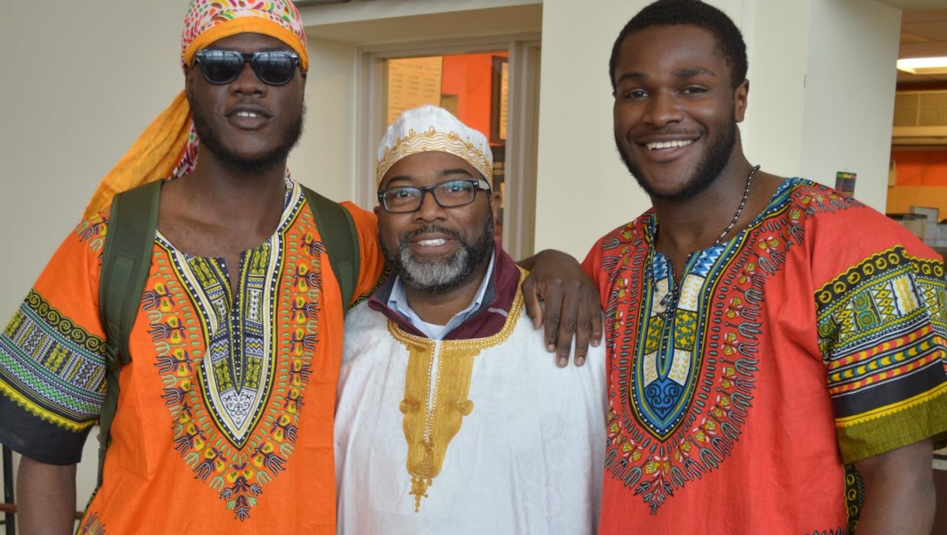 Calvin Hill poses with two male students