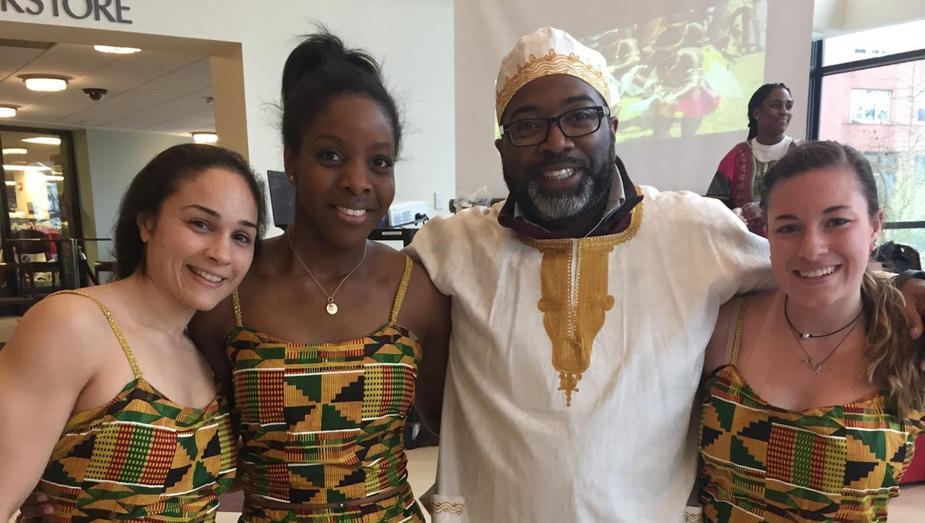 Calvin Hill poses with female students in traditional dress during African Cultural Day