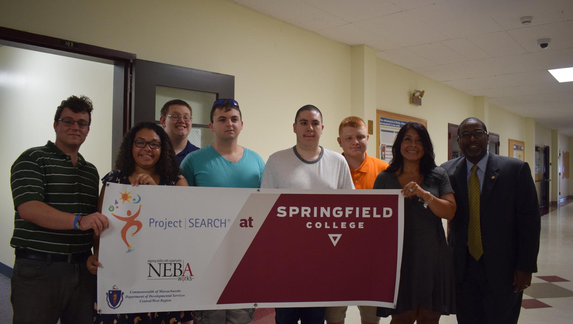 Project Search participants and staff stand with the banner. 