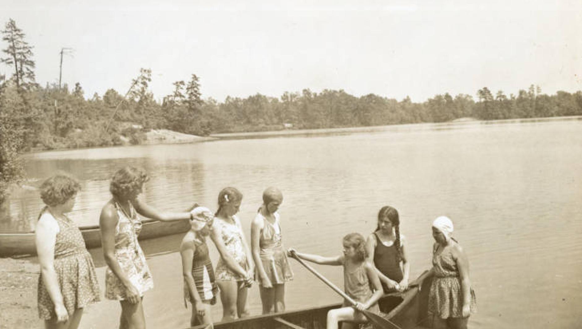 Girls get into a canoe on Camp Massasoit. 