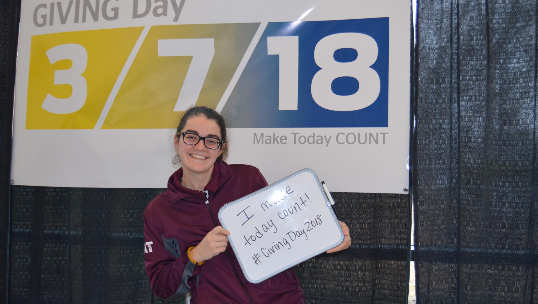 A student holds up a Giving Day sign.