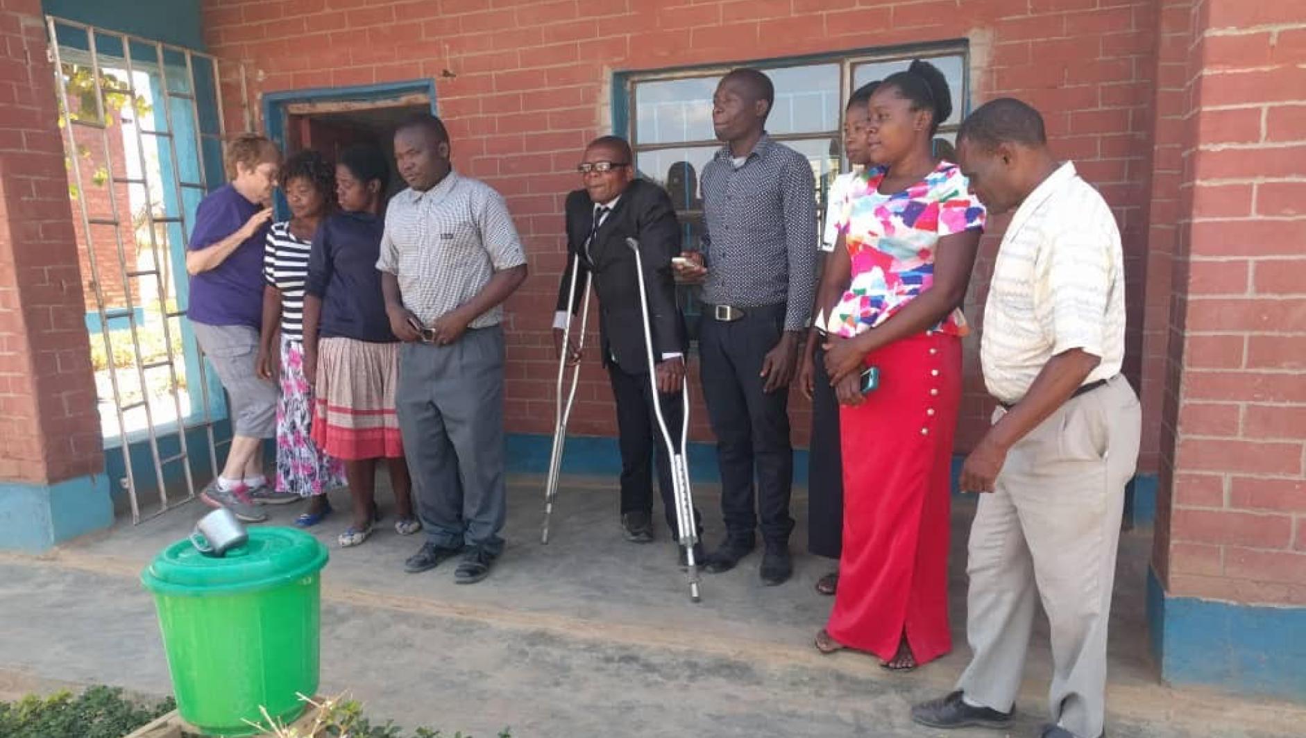 Staff with headmaster using the aluminum crutches we brought to him the summer before.
