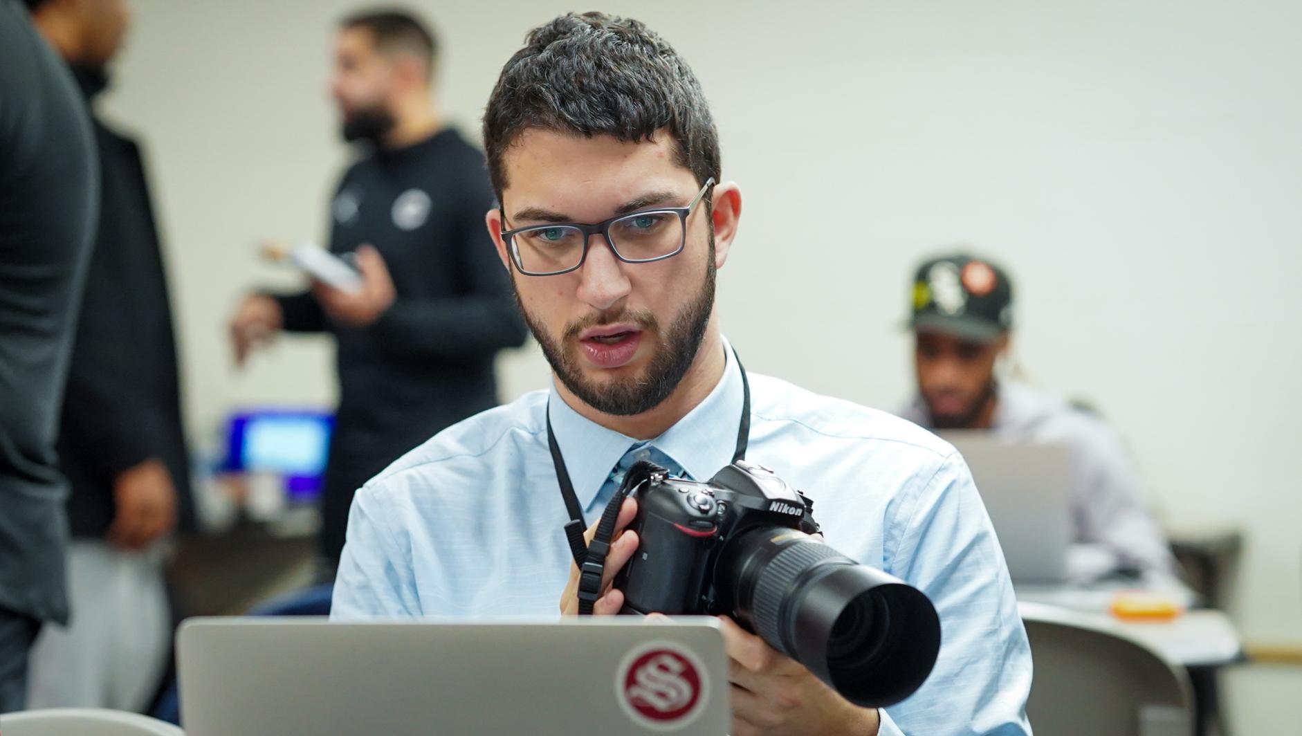 COSJ student at computer with a camera