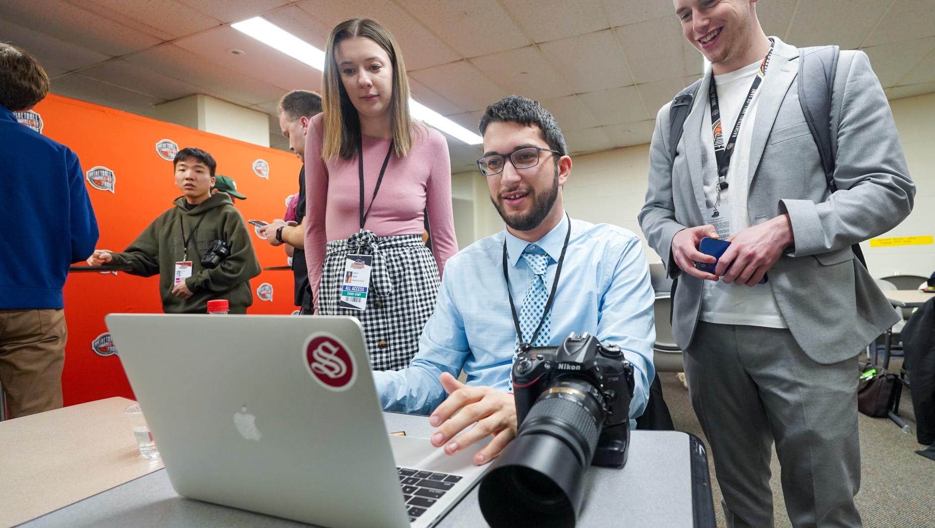 Communications and sports journalism students editing photos at computer