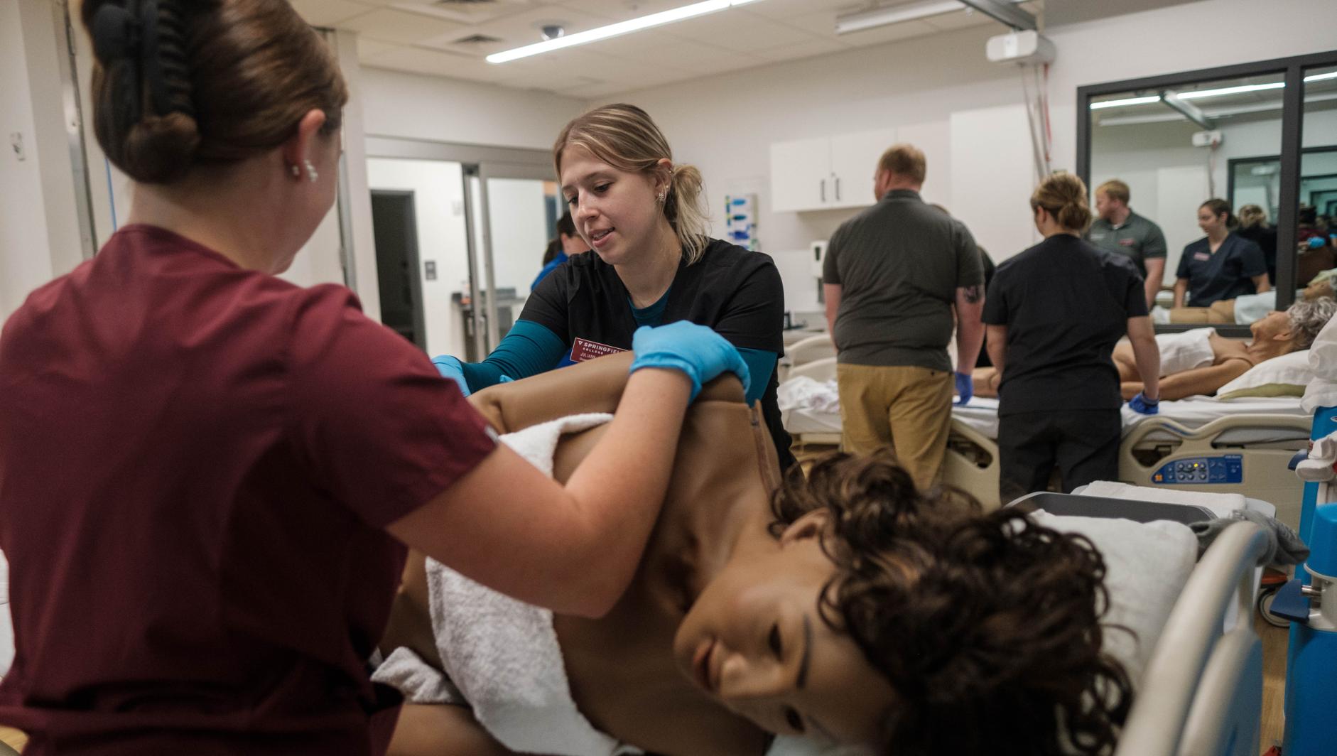 Springfield College Occupational Therapy students work with realistic simulation manikins to develop bed level care skills for dependent clients inside the Robotti Simulation Center at the Health Sciences Center