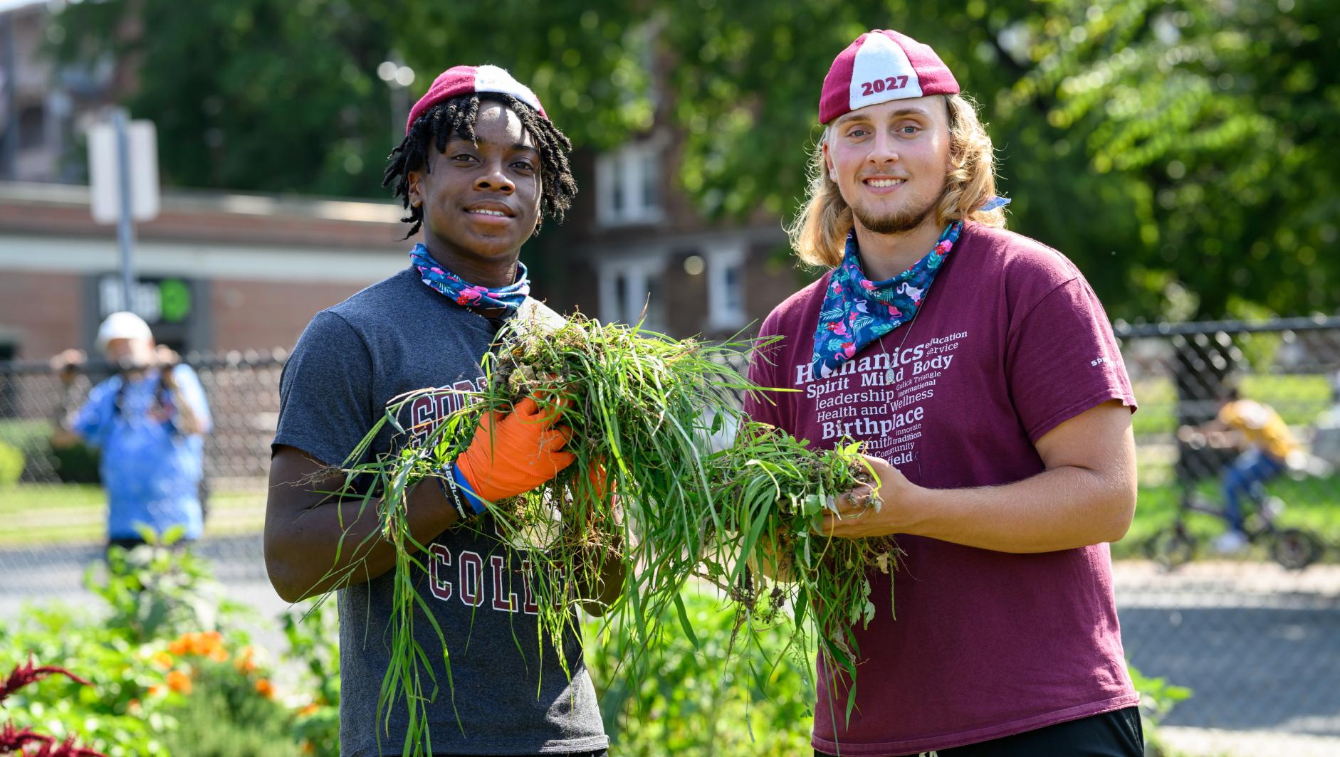Male students holding a pile of weeds from garden