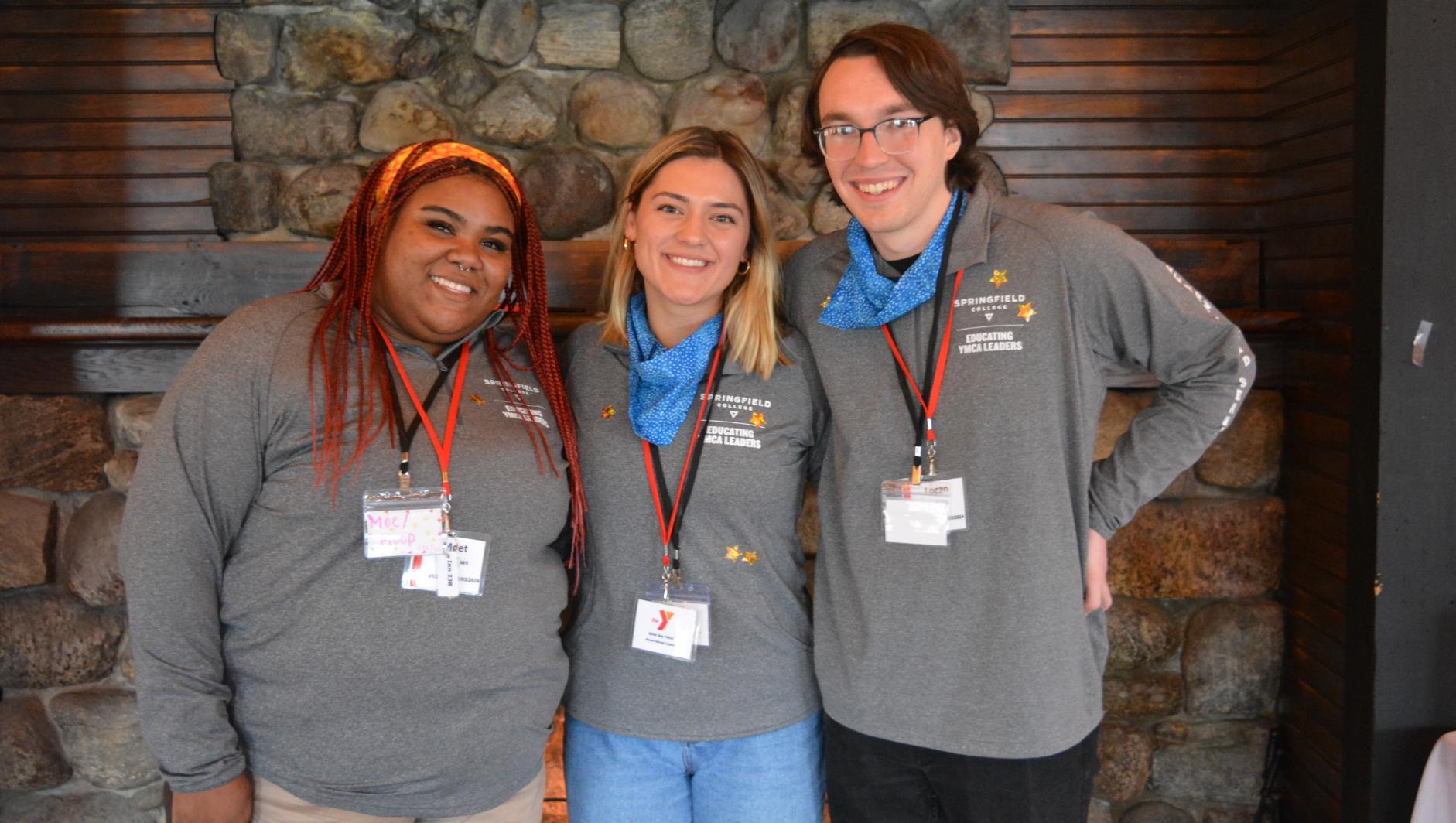 Three students standing in front of fireplace at annual leadership summit