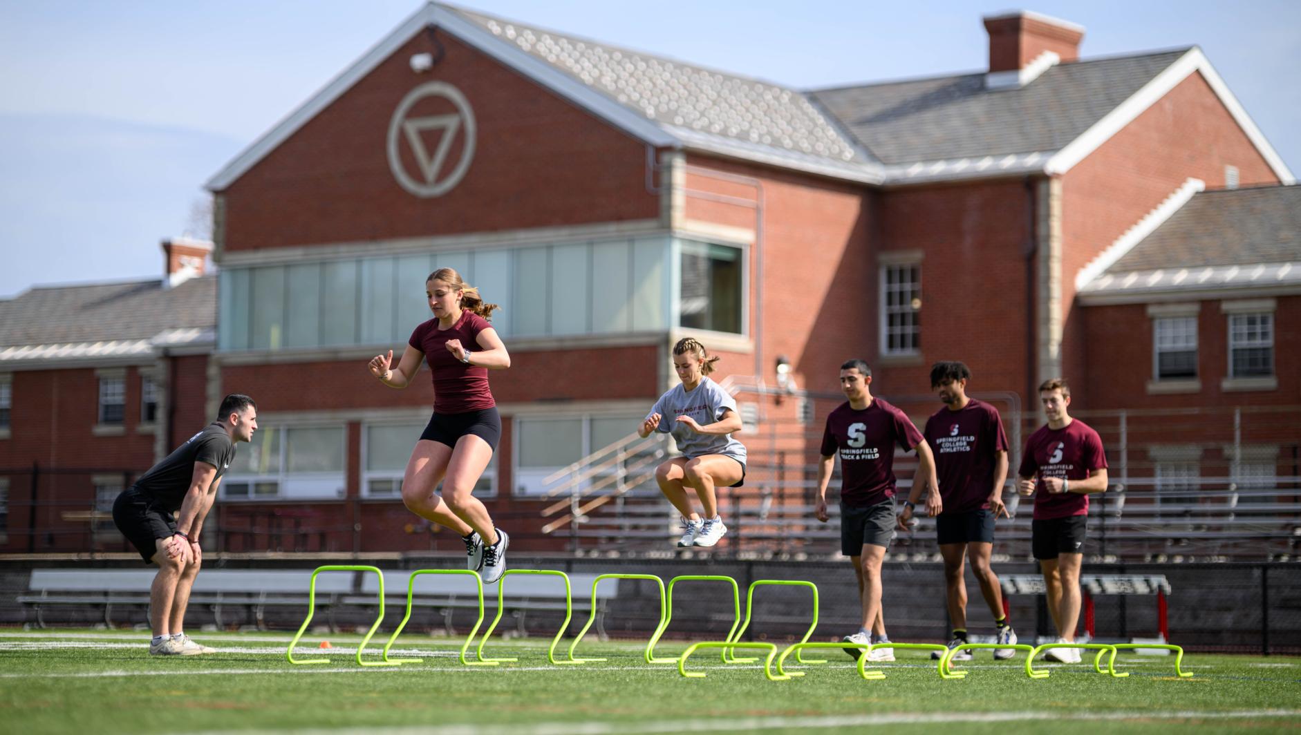 Graduate students enrolled in the Springfield College Strength and Conditioning masters program study with student athletes outside on Stagg Field on April 10, 2024