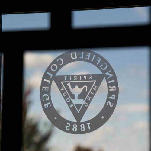 The Springfield College seal is on the window of the door on campus