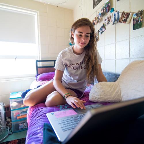 Student working on laptop in her residence hall at Springfield College