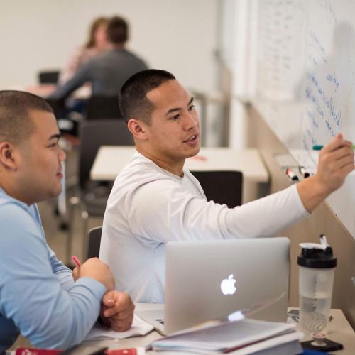 Students write on the white board in the Learning Commons