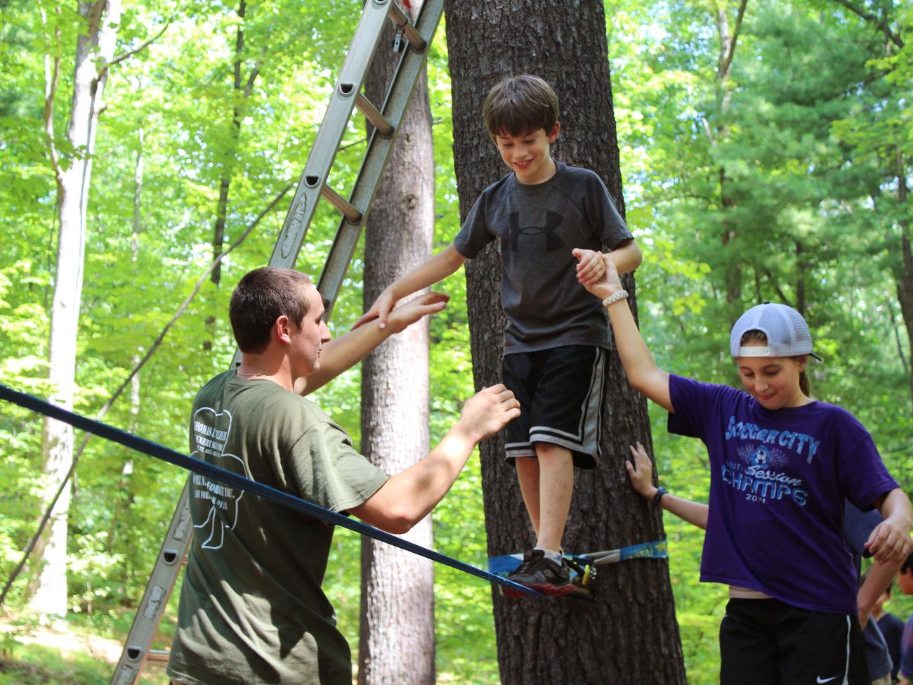 A camper walks on a tight rope during the topes course at Camp Massasoit.