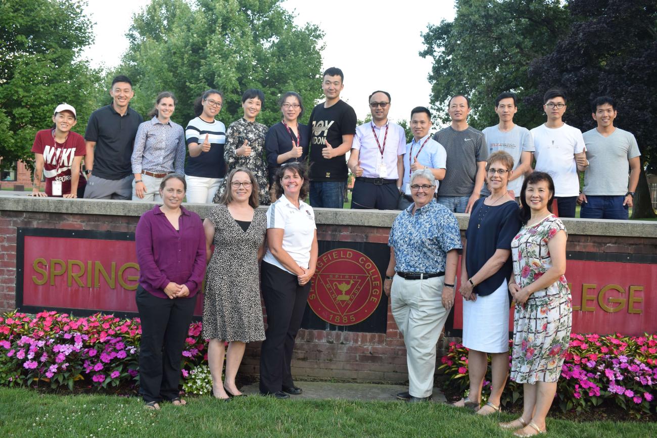 Springfield College faculty and visiting Chinese instructors pose before the college sign