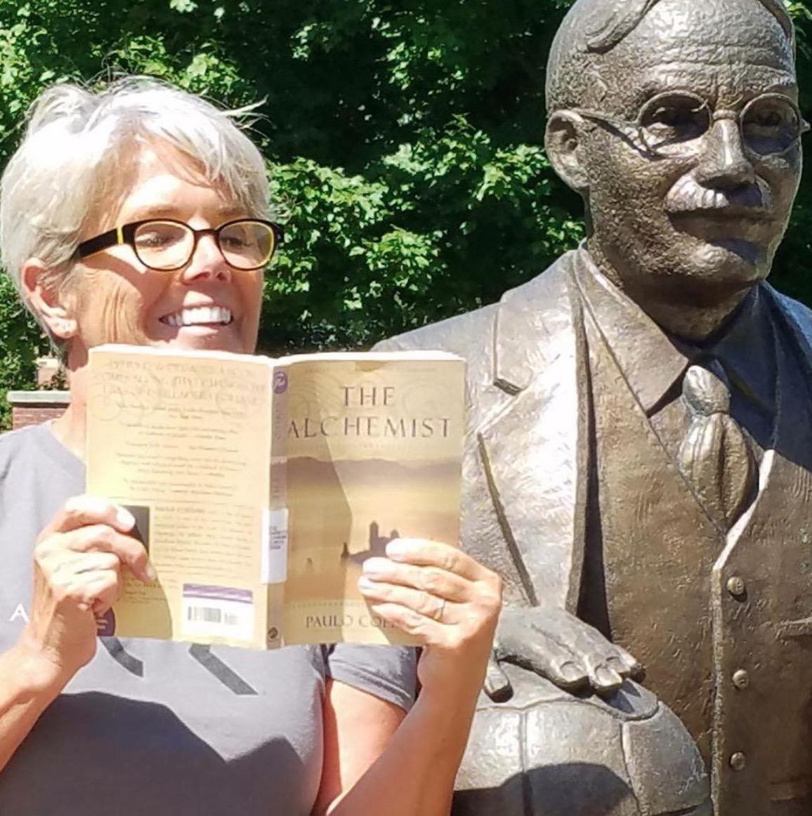 President Mary Beth Cooper reads Paulo Coelho's The Alchemist while sitting next to the James Naismith statue. 