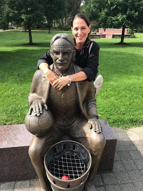 Marianna Newman stands with the James Naismith statue on the Springfield College campus. 