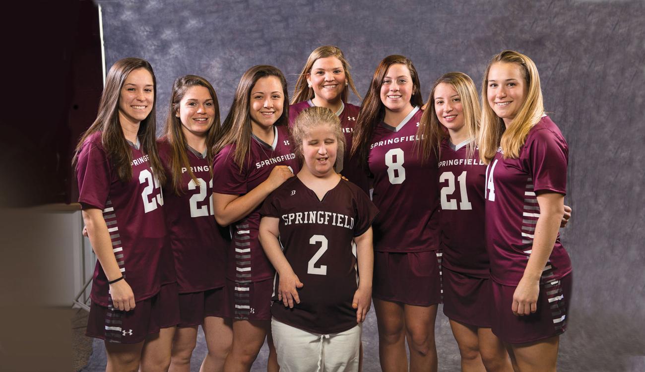 Team Impact participant Jillian Allair stands with the Springfield College Women's Lacrosse team