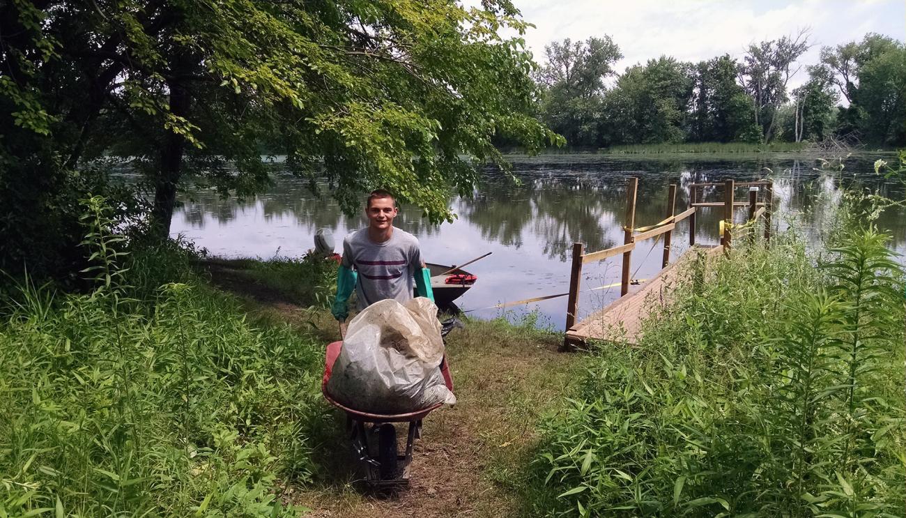 Andre Levesque '18, onsite pushing a wheelbarrow at his internship with the Connecticut River Conservatory