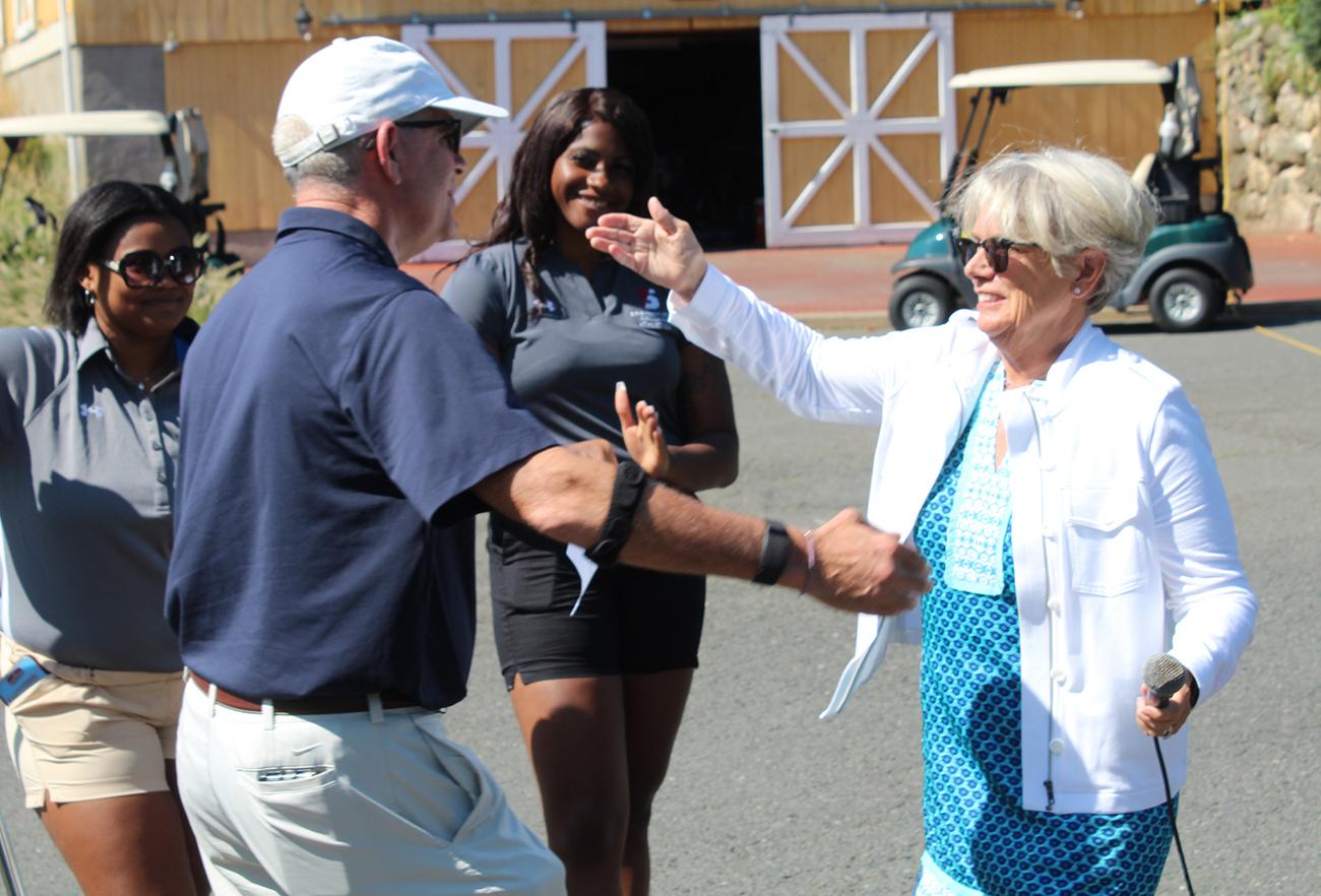 President Cooper is shown reaching out to greet golf classic honoree Steve Windwer