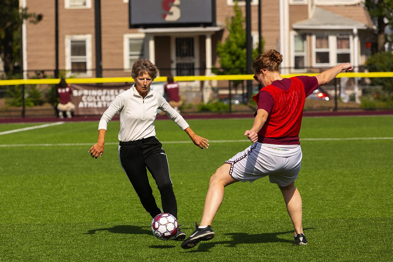 two women playing soccer on an outdoor field