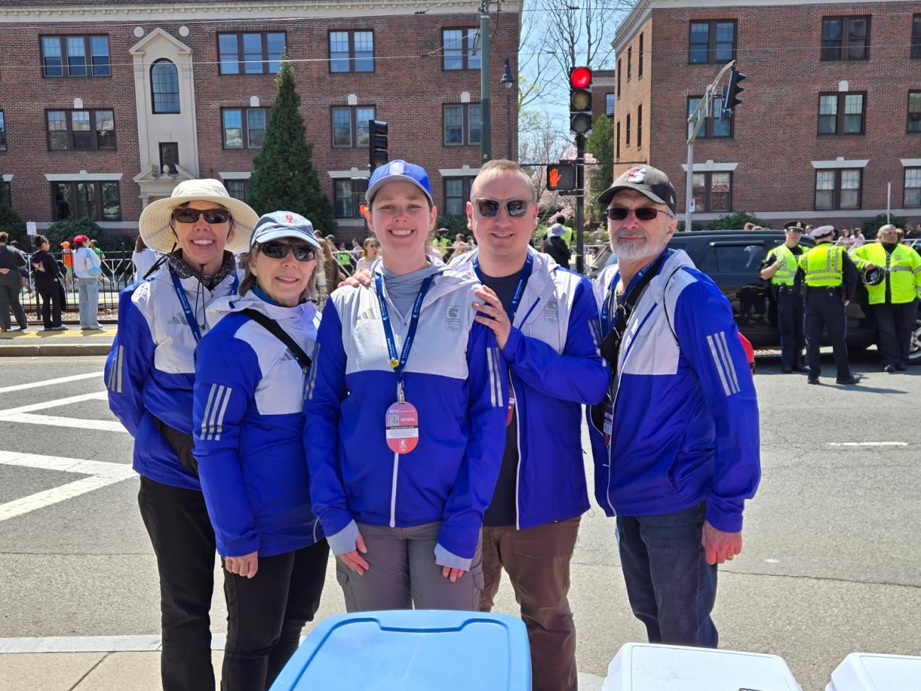 Laurel Ford Smith '73 (far left) and her husband RP Smith '73 G'77 CAS '84 (far right) with volunteers at the 35 kilometers professional athlete fluid distribution area at the 2025 Boston Marathon.