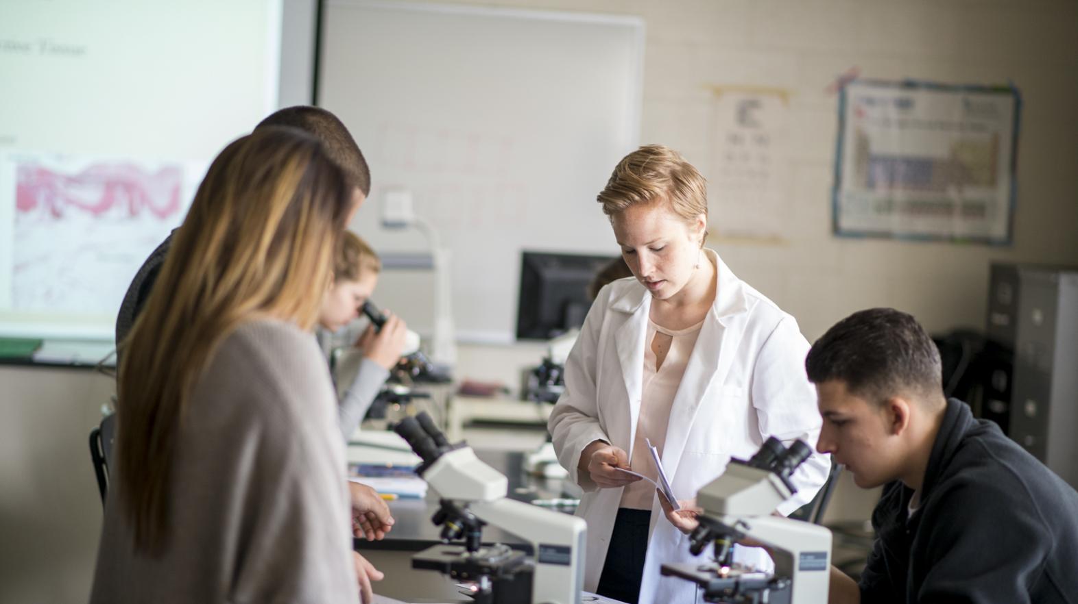 A faculty member works with students in a lab