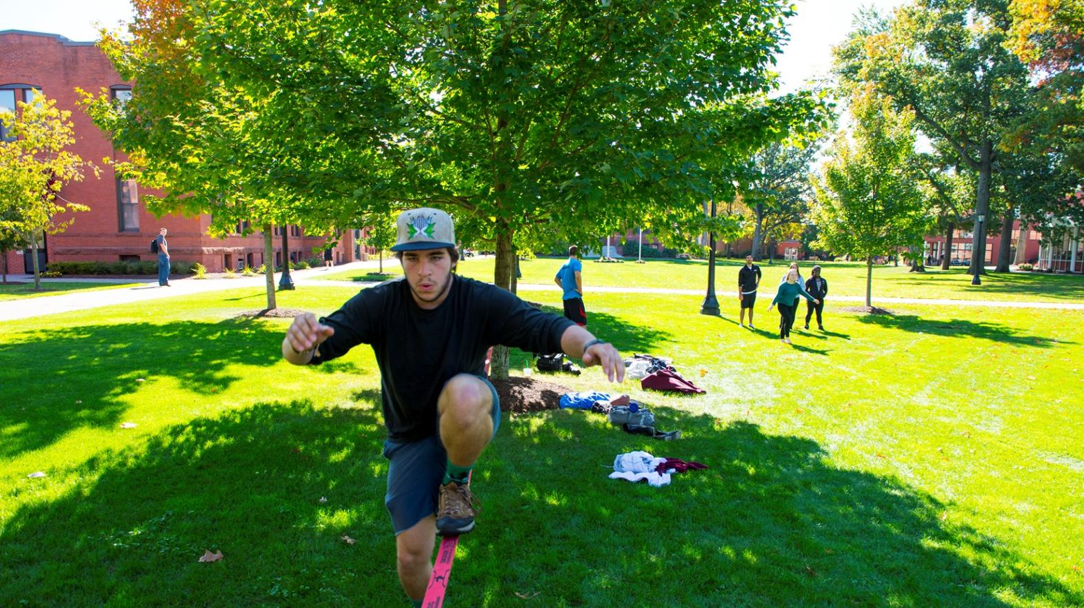 A student walks on a tight rope on the campus green