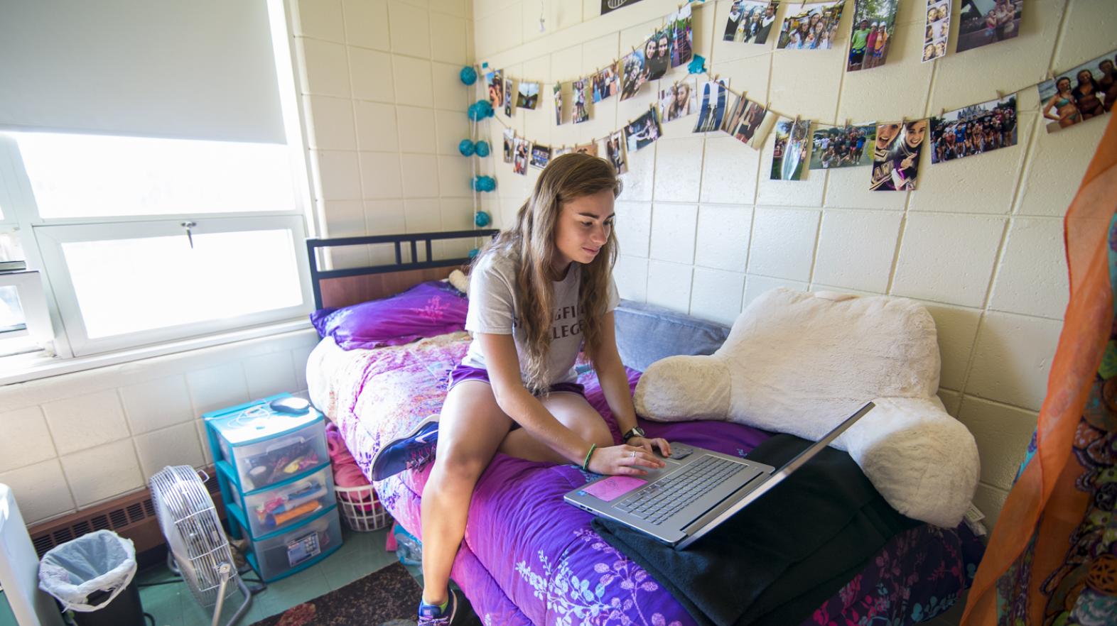 A students works on her laptop in her residence hall room