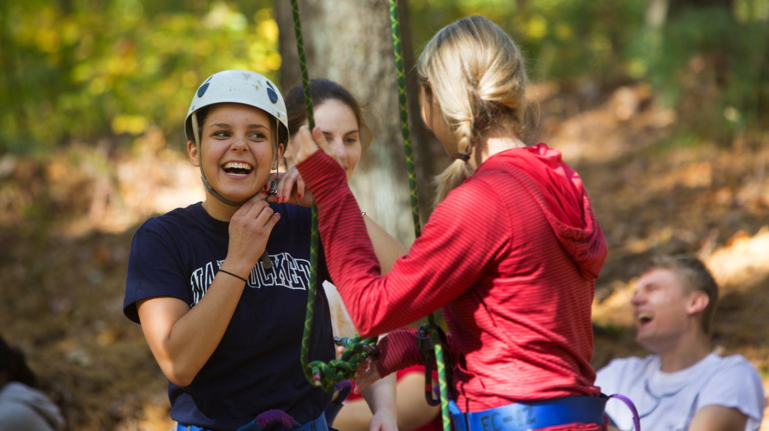 Female students laugh as they participate in the challenge course at East Campus