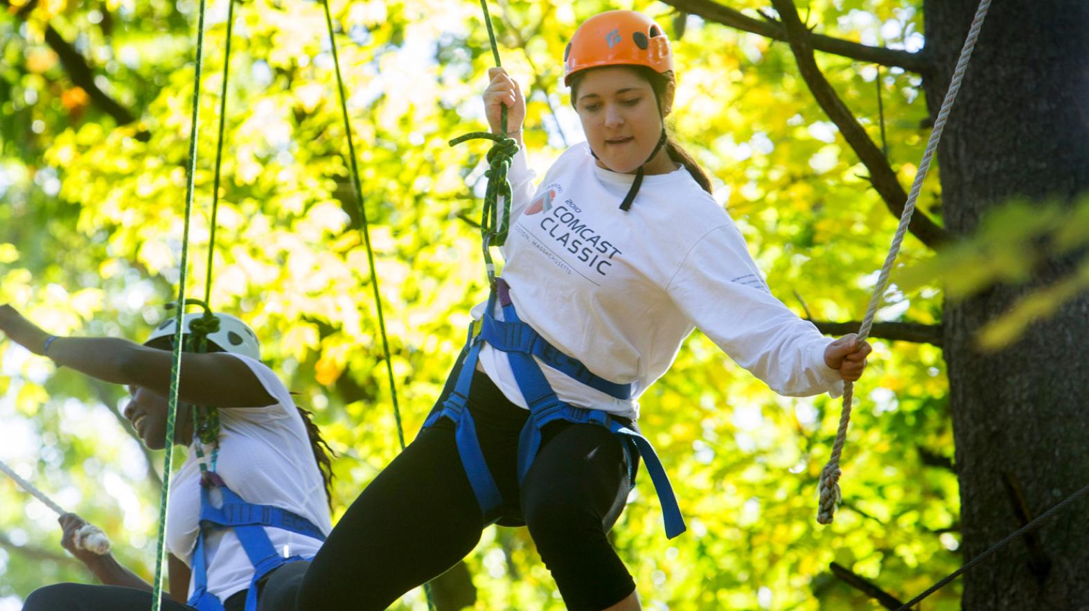 Female students in a tree as they navigate the challenge course at East Campus