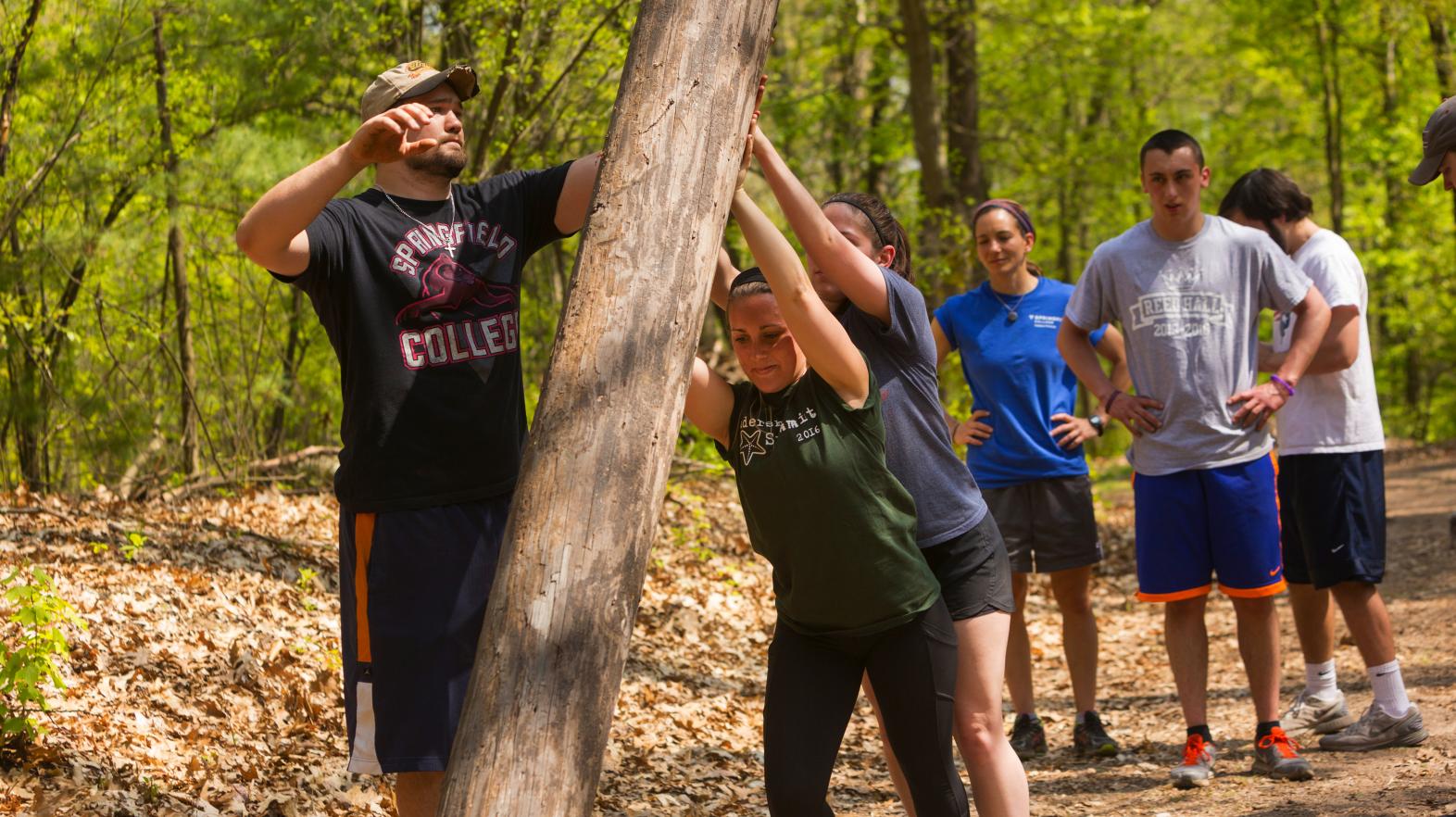 Students work together to lift a log during Outdoor Pursuits at Springfield College