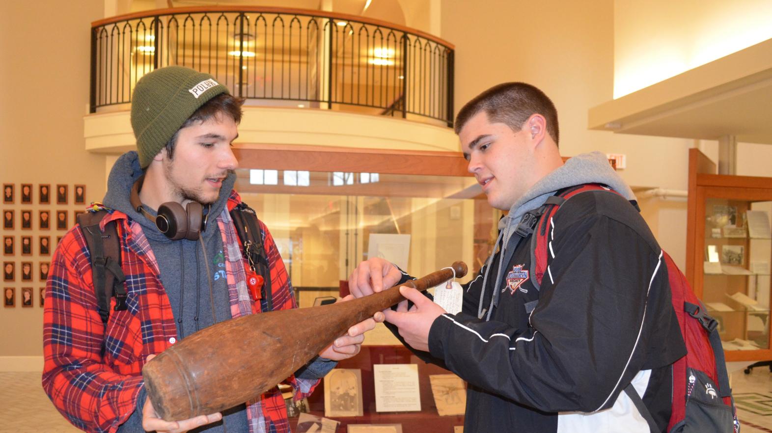 Two students examine a historic piece of pottery in the Springfield College experience.